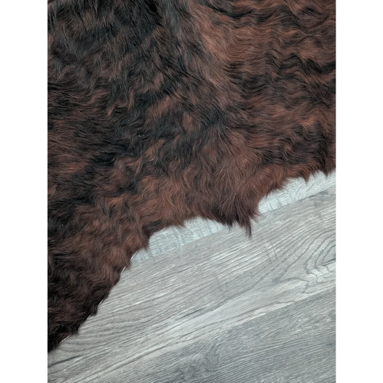 A large cowhide rug with beautiful dark brown and black fur showcasing unique characteristics and natural texture