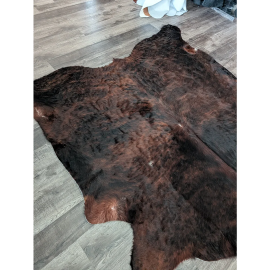 Large cowhide rug in rich dark brown with unique characteristics and natural textured fur perfect for beautiful rugs