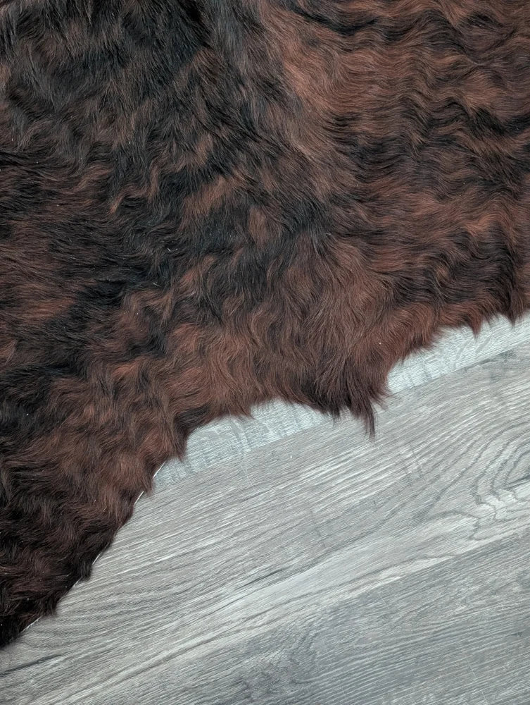 A large cowhide rug with beautiful dark brown and black fur showcasing unique characteristics and natural texture