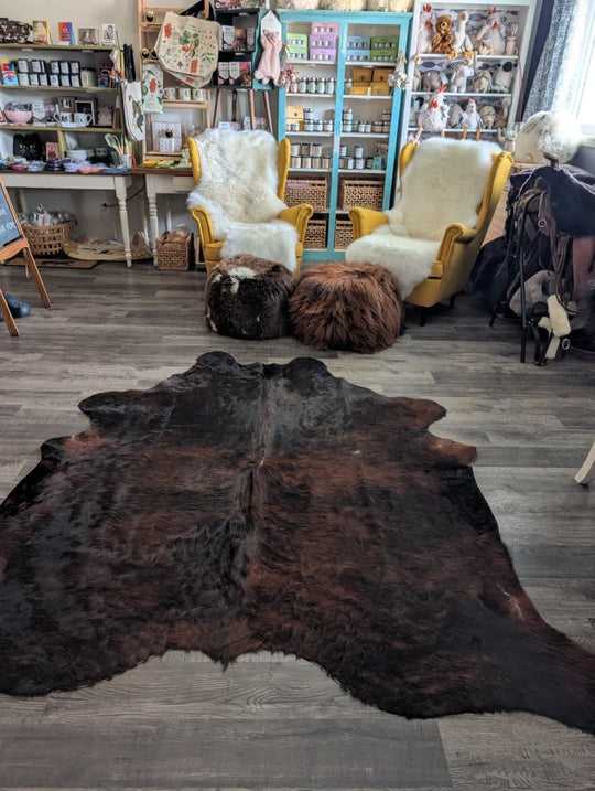 Large cowhide rug with dark brown textured hide and black patches showcasing unique characteristics for beautiful rugs