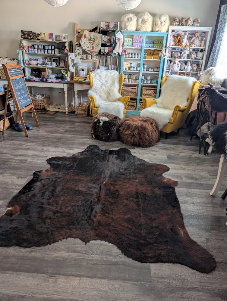 Dark brown large cowhide rug with natural fur texture and unique characteristics perfect for beautiful rugs displays