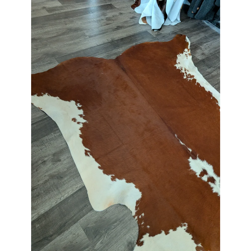 Large cowhide rug with brown and white natural irregular patches showcasing unique characteristics and beautiful rugs design