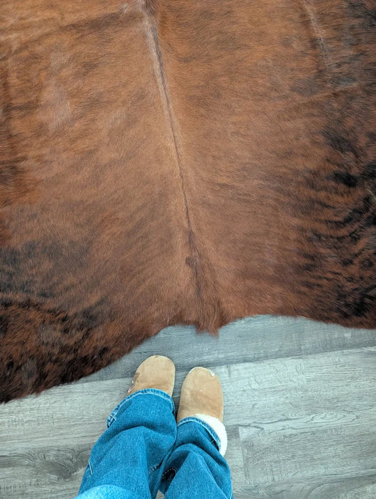 Brown large cowhide rug with natural fur texture and subtle darker patches showcasing unique characteristics