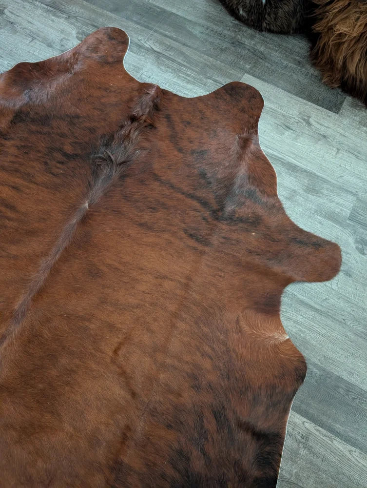 Brown and black large cowhide rug with natural fur texture showcasing unique characteristics and beautiful rugs design