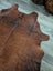 Brown and black large cowhide rug with natural fur texture showcasing unique characteristics and beautiful rugs design