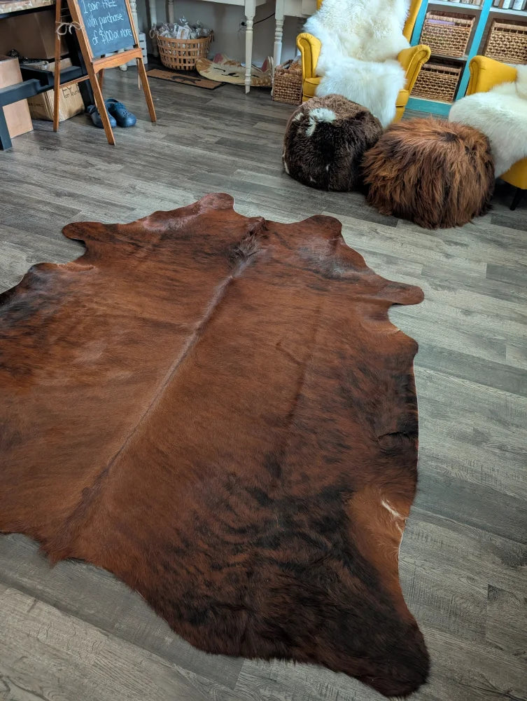 Rich brown large cowhide rug with natural fur texture and irregular edges showcasing unique characteristics