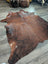 Brown large cowhide rug with natural fur texture and irregular edges showcasing unique characteristics for beautiful rugs