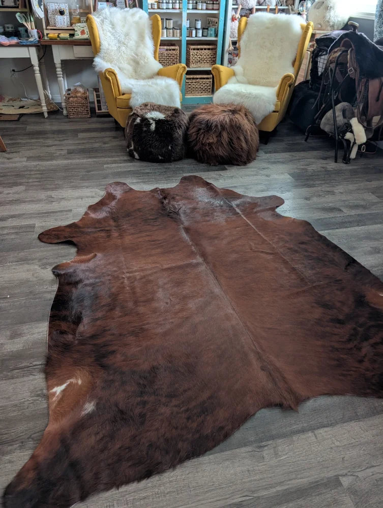 Brown large cowhide rug with natural fur texture and irregular edges showcasing unique characteristics and beautiful rugs