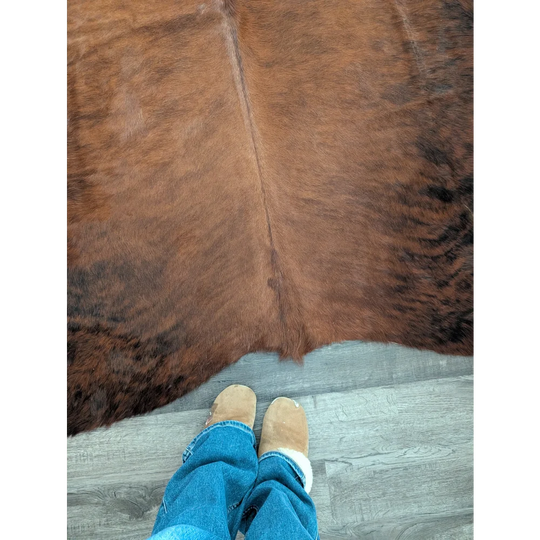 Brown large cowhide rug with natural fur texture and subtle darker patches showcasing unique characteristics