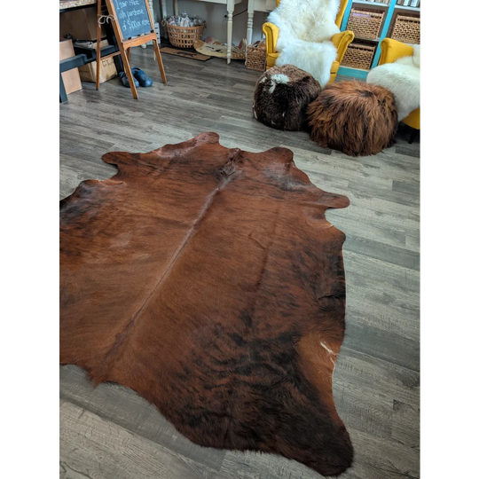 Rich brown large cowhide rug with natural fur texture and irregular edges showcasing unique characteristics