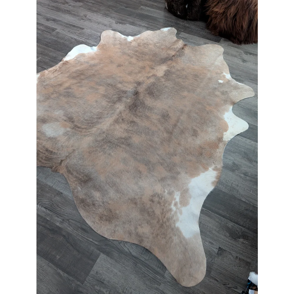 A large cowhide rug in natural tan and white with a soft textured surface showcasing unique characteristics