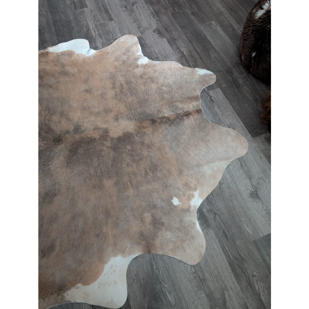 A large cowhide rug with natural brown and white colors featuring beautiful rugs and unique characteristics