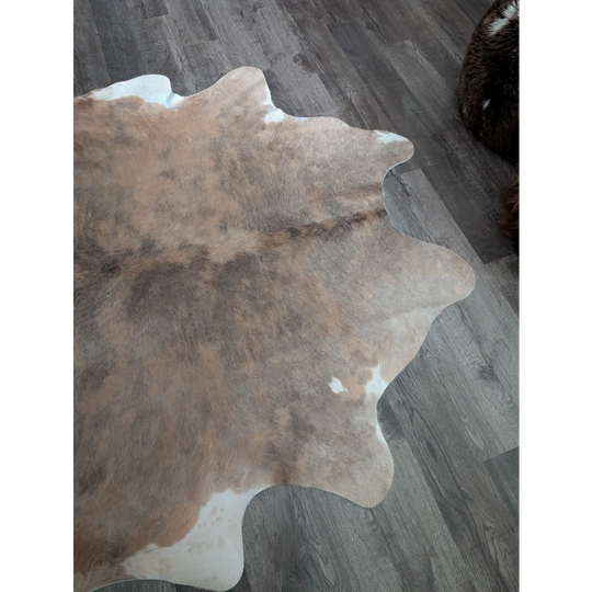 A large cowhide rug with natural brown and white colors featuring beautiful rugs and unique characteristics