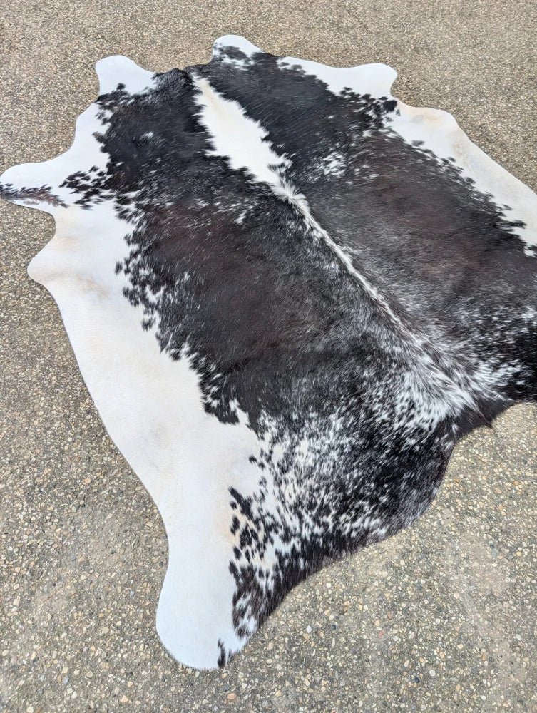 Large cowhide rug with black and white natural irregular edges showcasing unique characteristics and beautiful rugs style