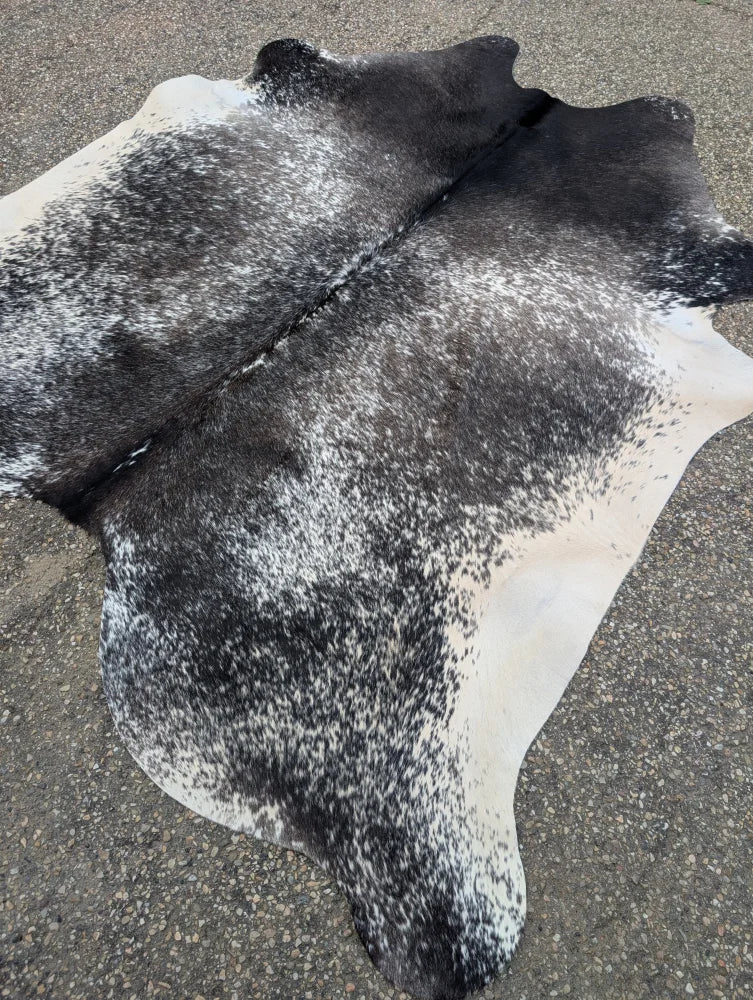Extra large black and white speckled cowhide rug with natural edges showcasing unique characteristics for beautiful rugs