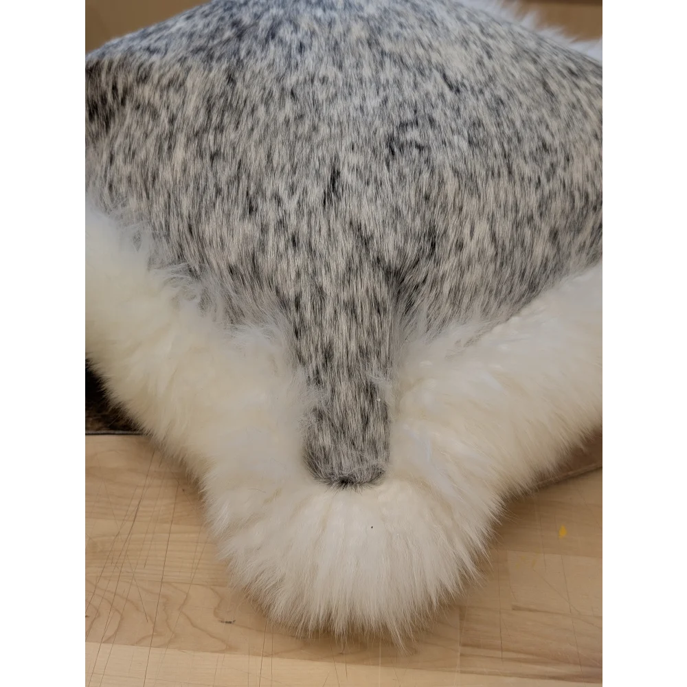 A plush gray and white speckled faux fur merino sheepskin cushion with fluffy white border by angus oliver canada