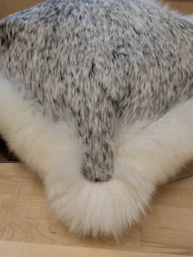 A plush gray and white speckled faux fur merino sheepskin cushion with fluffy white border by angus oliver canada