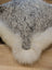 A plush gray and white speckled faux fur merino sheepskin cushion with fluffy white border by angus oliver canada