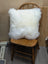 White fluffy merino sheepskin cushion resting on wooden chair by angus oliver canada