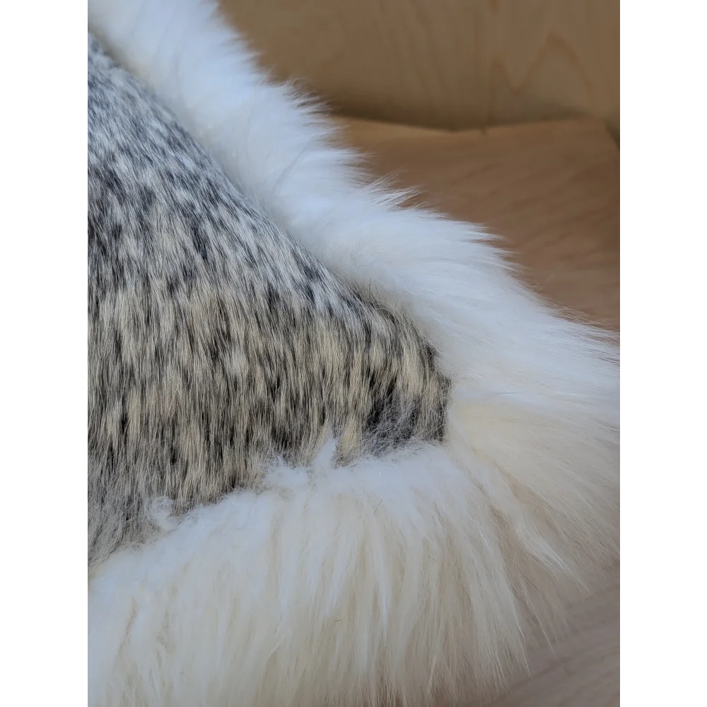 A cowhide and merino sheepskin cushion with a mottled gray and white plush throw and soft white border by Angus Oliver Canada