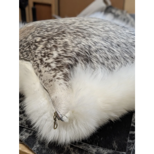 A plush cowhide and merino sheepskin cushion with speckled gray top and fluffy white trim by angus oliver canada