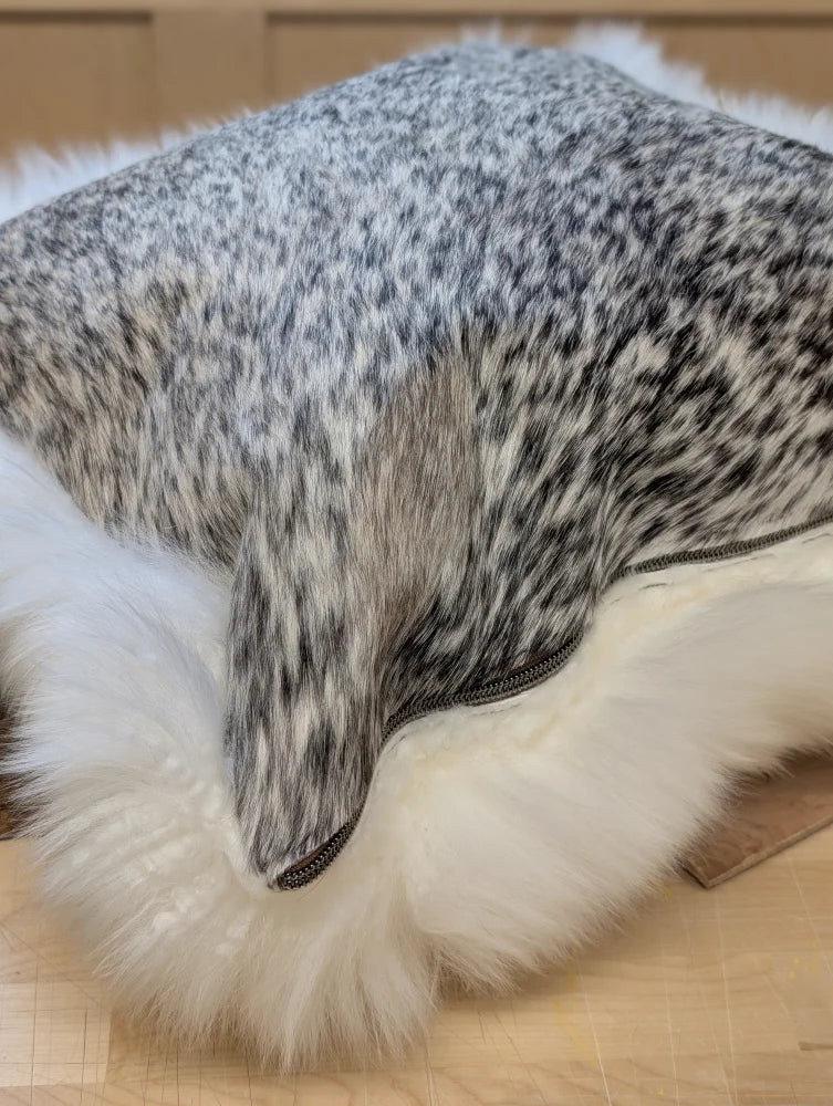 A plush cowhide and merino sheepskin cushion in speckled gray with white fluffy trim by angus oliver canada