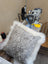 A plush gray and white merino sheepskin cushion with soft fluffy white fur trim by angus oliver canada