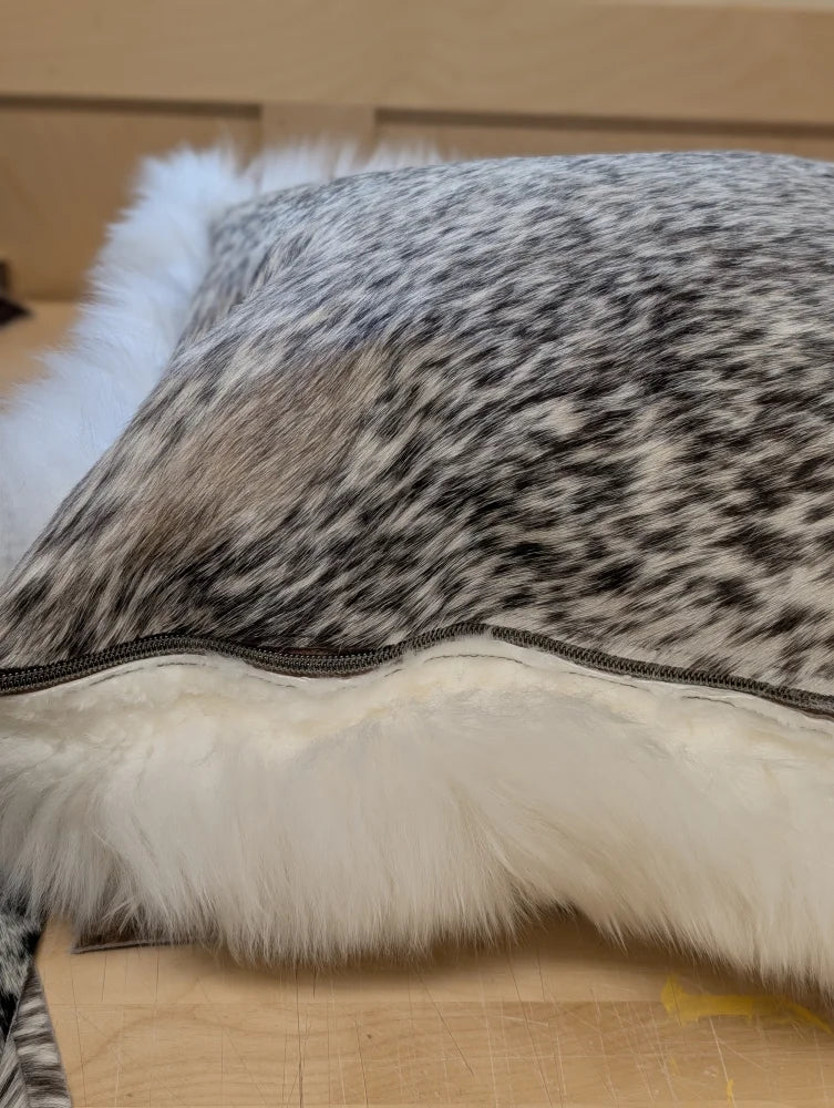 A plush gray and white merino sheepskin cushion with soft white faux fur trim by angus oliver canada