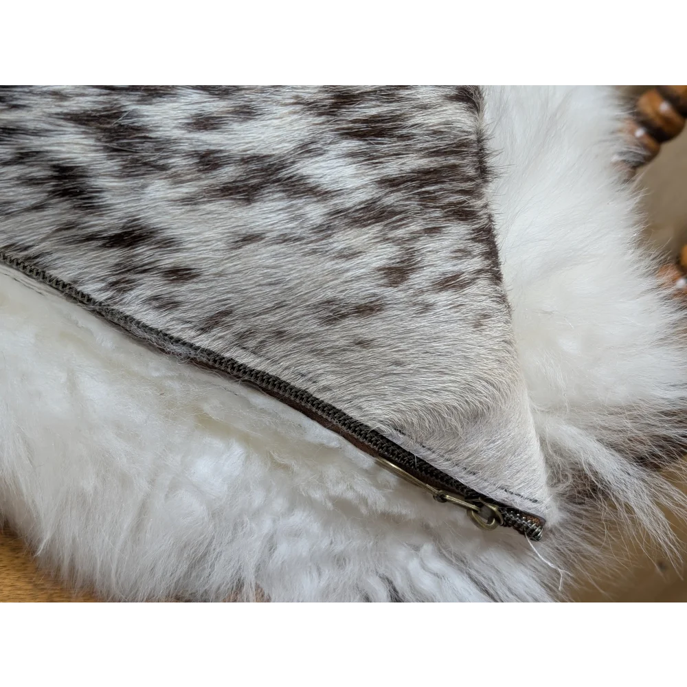 A cozy cowhide and merino sheepskin cushion with gray black speckled exterior and plush white lining by angus oliver canada