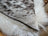 A cozy cowhide and merino sheepskin cushion with gray black speckled exterior and plush white lining by angus oliver canada