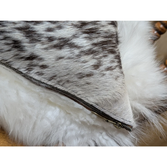 A cozy cowhide and merino sheepskin cushion with gray black speckled exterior and plush white lining by angus oliver canada