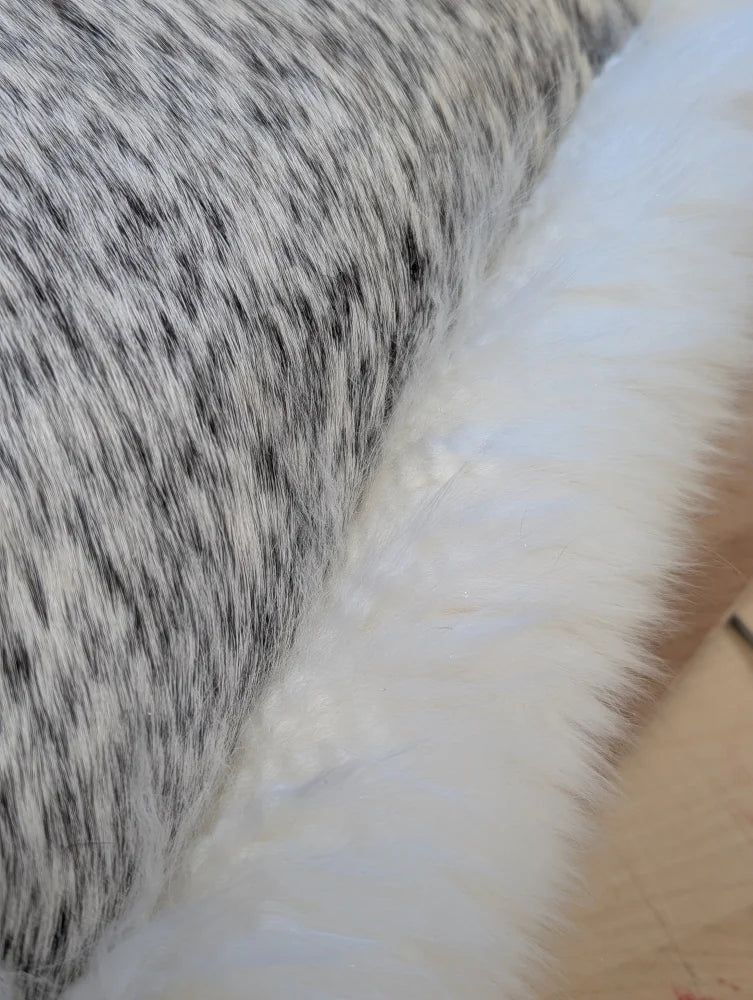 A cowhide and merino sheepskin cushion with black and white speckled faux fur and soft white fabric by angus oliver canada