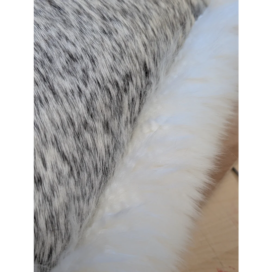 A cowhide and merino sheepskin cushion with black and white speckled faux fur and soft white fabric by angus oliver canada