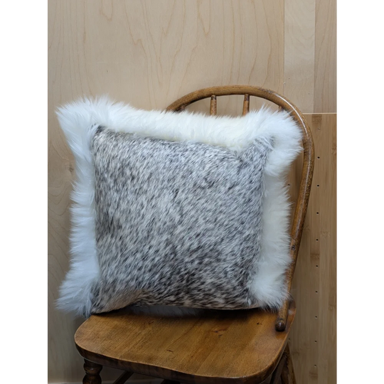 A cozy cowhide and merino sheepskin cushion with speckled gray center and fluffy white fur trim by angus oliver canada