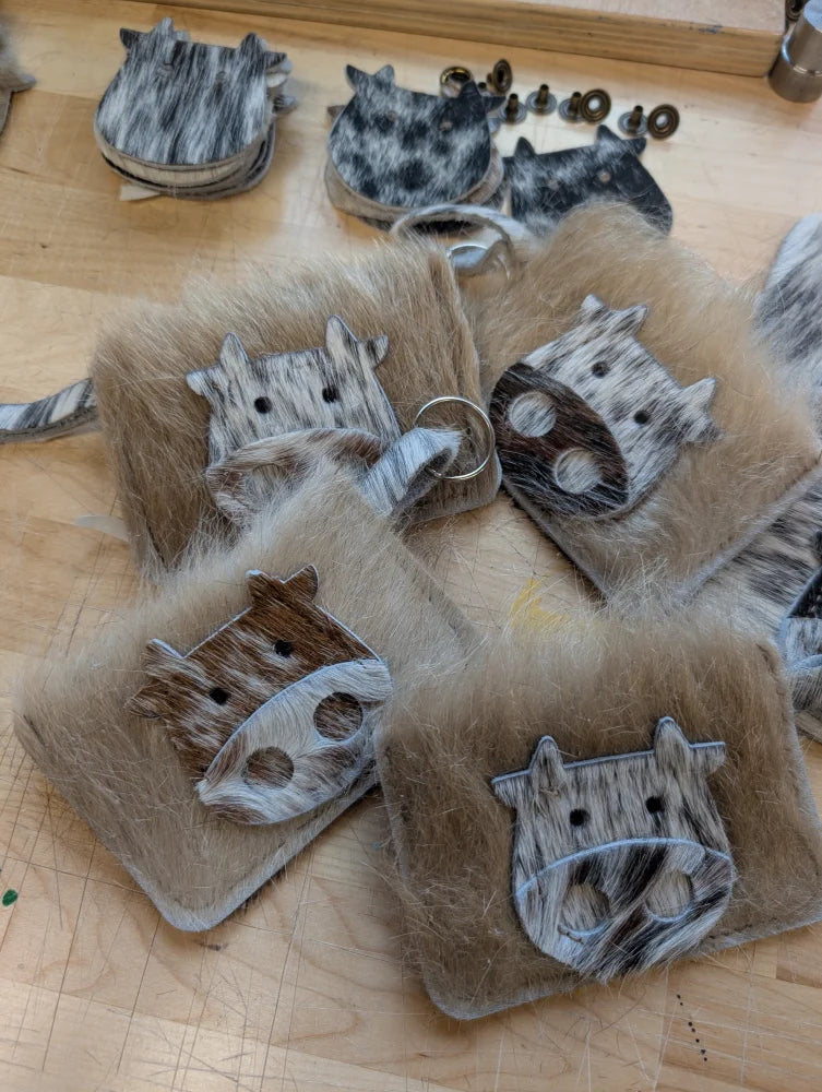 Faux fur cow face keychain card holders with black and white spotted leather accents for stylish card storage
