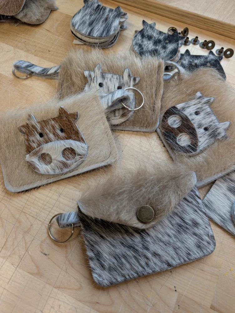 Cute cowhide keychain card holders made from natural textured hide with soft fur trim and metal hardware