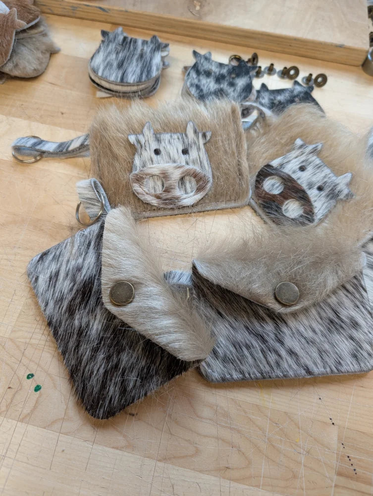 Cattle-print leather keychain card holders with embroidered cow faces and metal snap closures