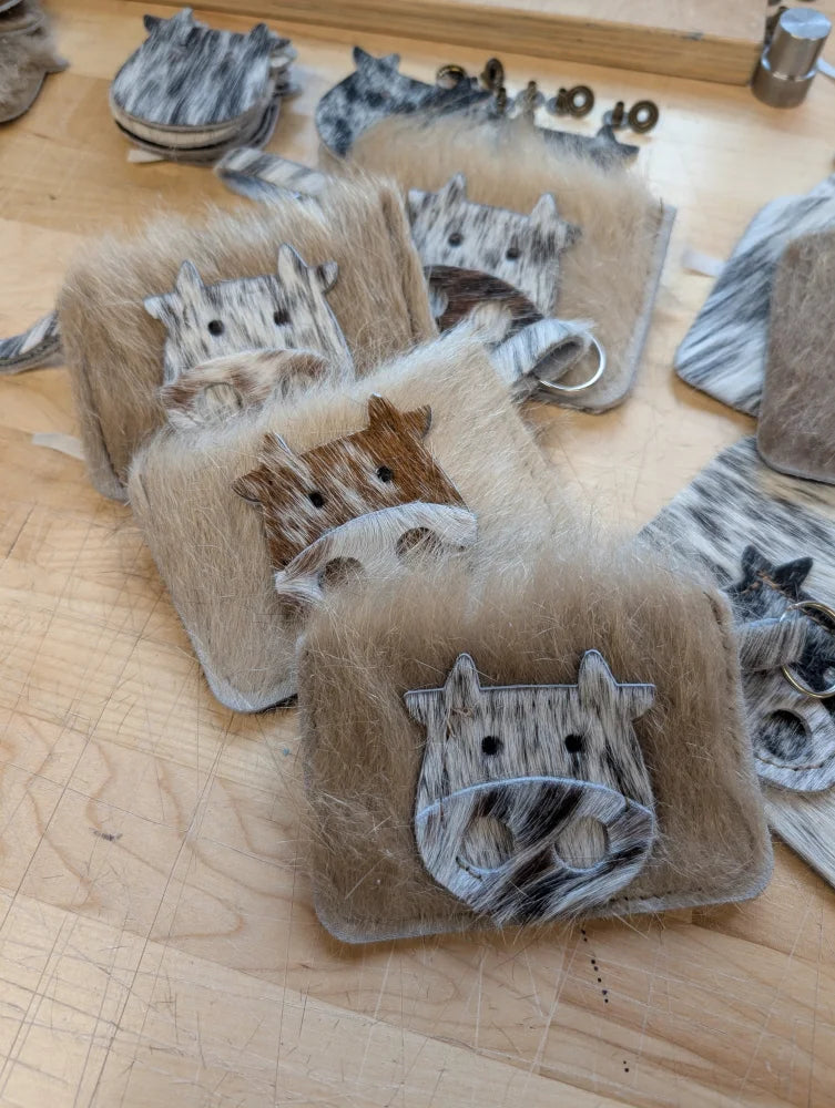 Faux fur cow face keychain card holders in natural and gray tones with stitched details for easy access