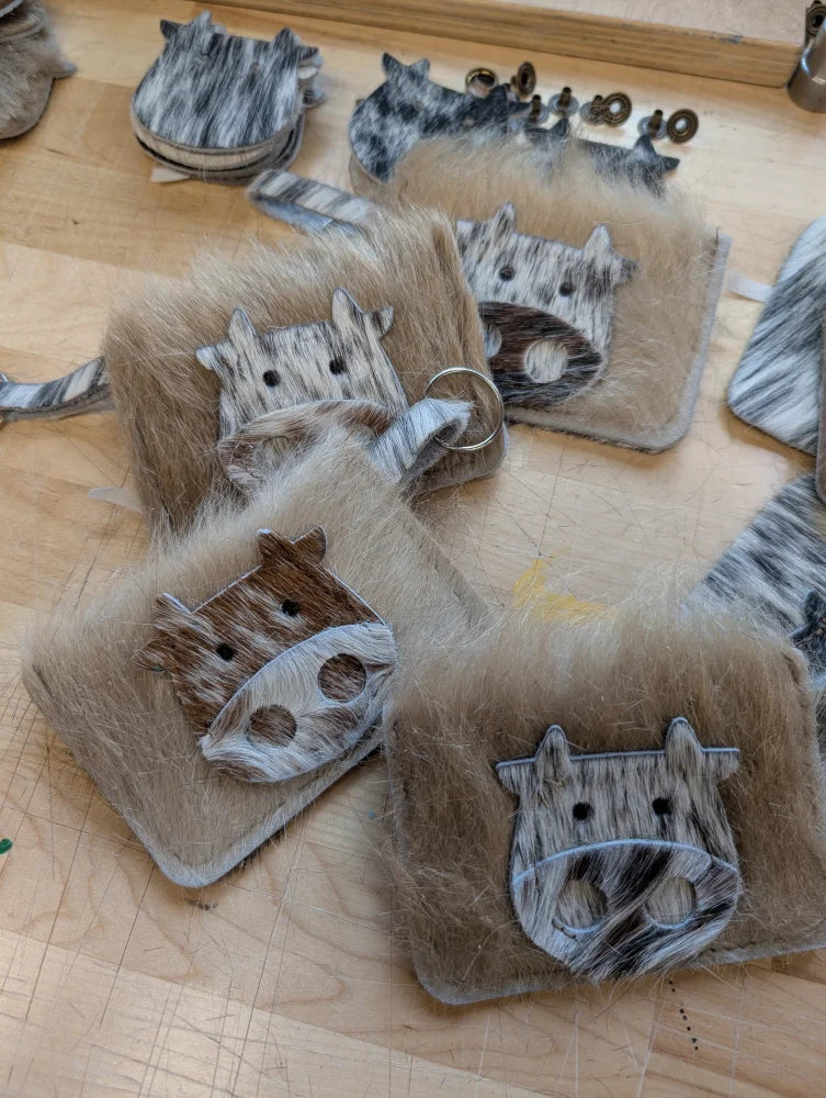 Faux fur cow-themed keychain card holders with gray and white marbled face design for stylish card storage