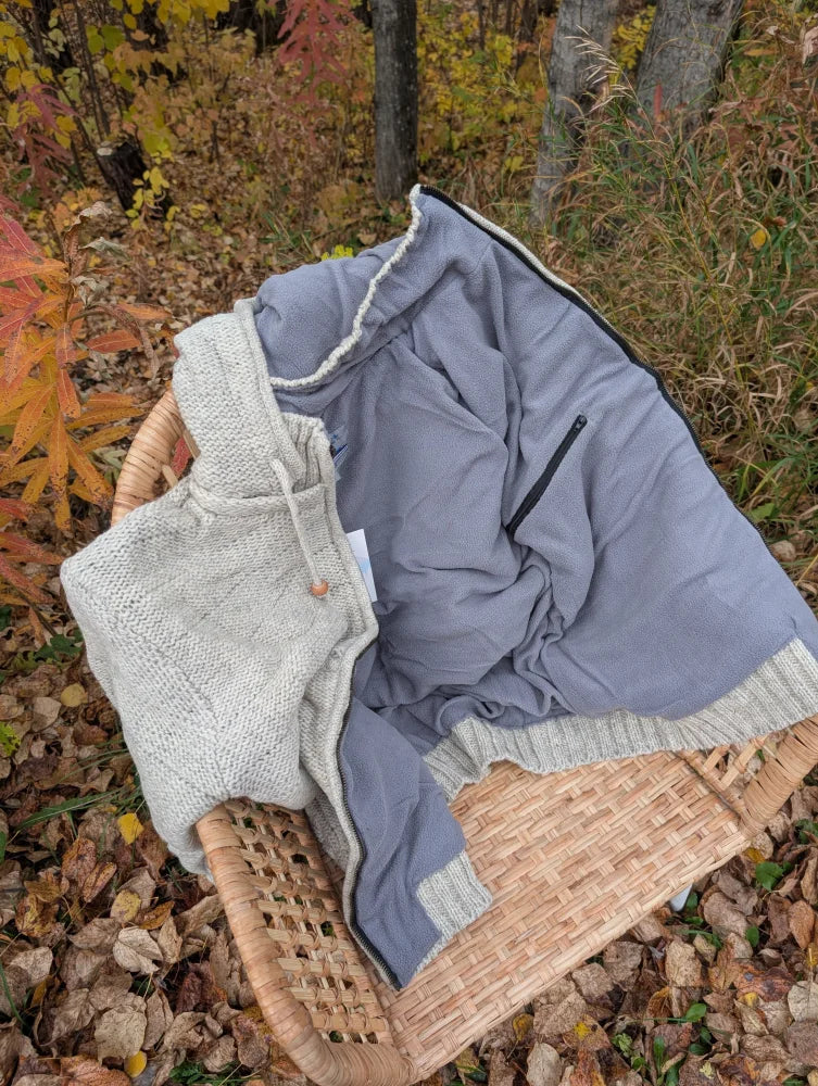 Cream woolen calgary cardigan soft fleece jacket in cozy gray with ribbed knit collar resting in woven basket