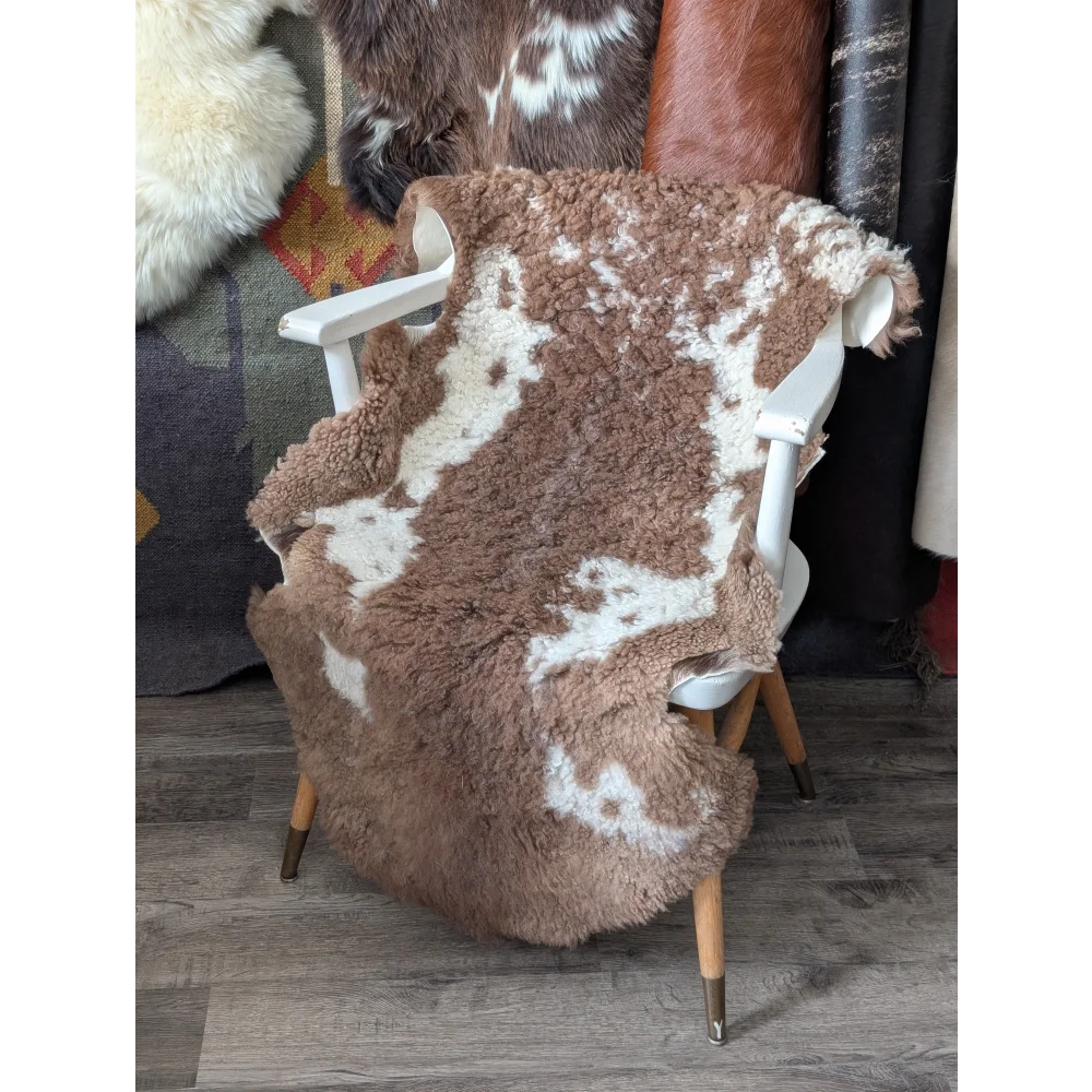 Fluffy cloud bedding sheepskin throw in natural colours on white chair
