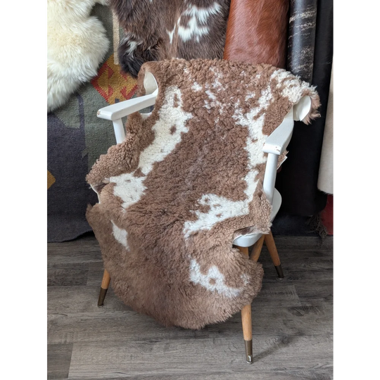 Fluffy cloud bedding sheepskin throw in natural colours on white chair
