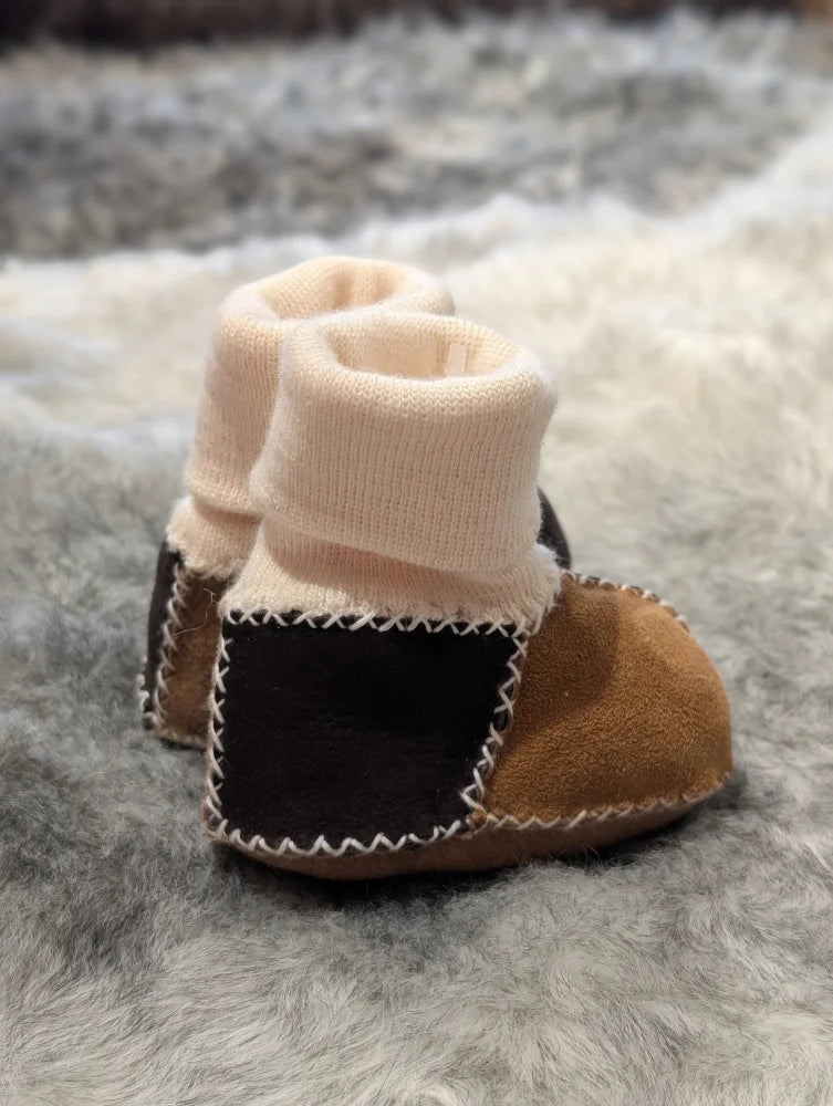 Cute sheepskin baby booties with knitted cuffs and patchwork design in stretchy fabric
