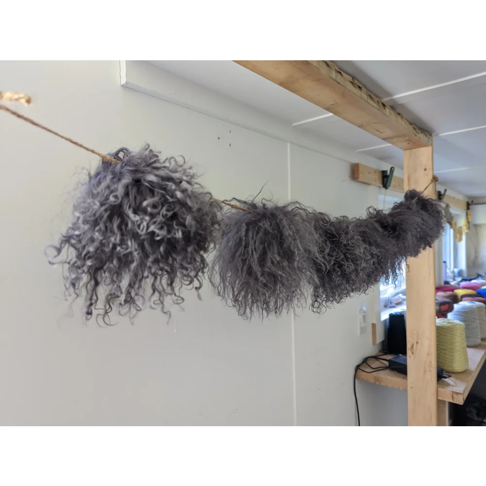 Dark grey sheepskin pom pom with gray curly wool on wooden stick