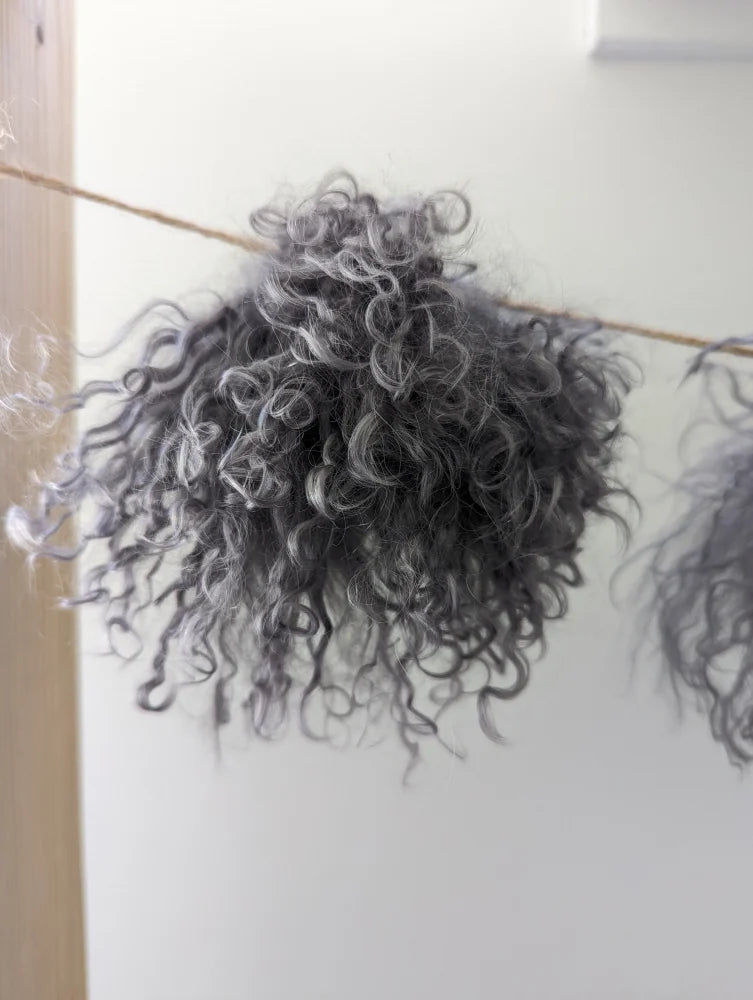 Dark grey sheepskin pom pom with grey curly hair wall decor