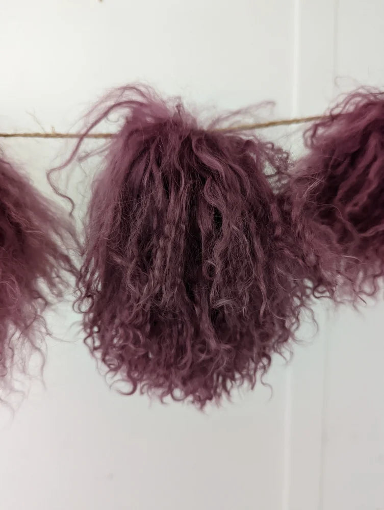 Dark pink sheepskin pom poms with maroon curly hair extension