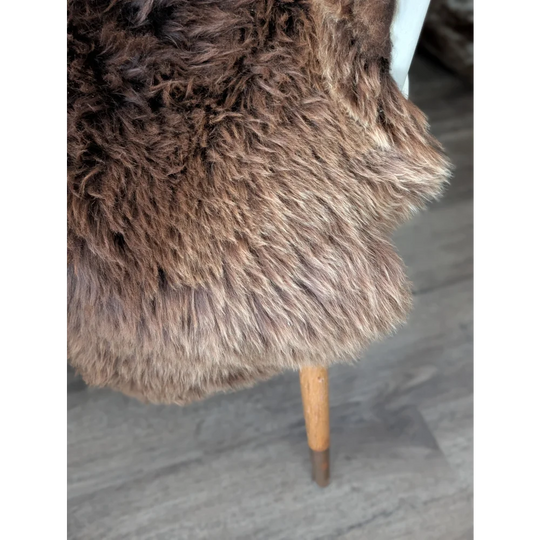Gorgeous fluffy British sheepskin rug draped over wooden chair leg