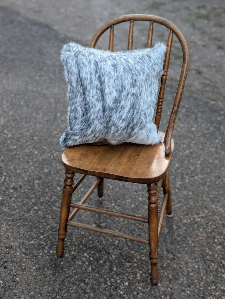 A cozy light blue and gray double sided cowhide cushion with a soft faux fur texture on an antique wooden chair