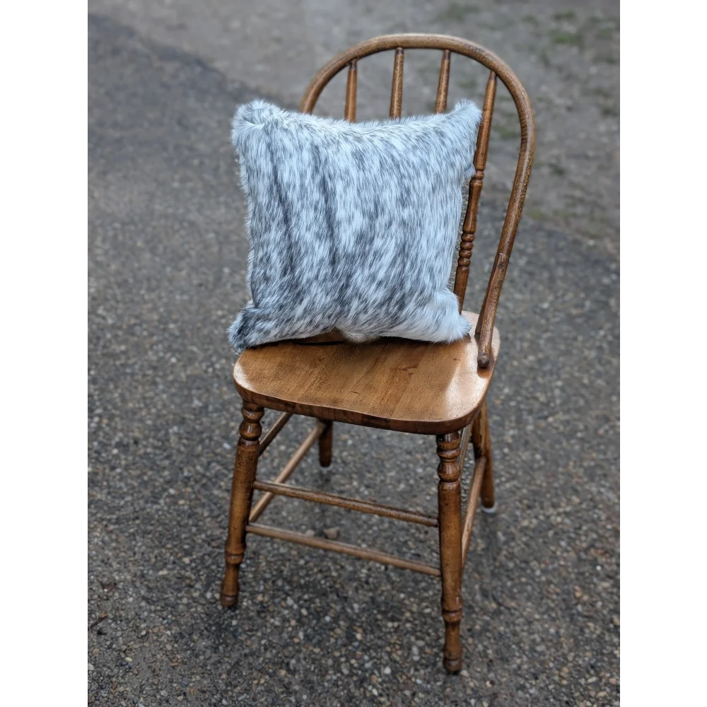 A cozy light blue and gray double sided cowhide cushion with a soft faux fur texture on an antique wooden chair