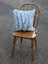 A cozy light blue and gray double sided cowhide cushion with a soft faux fur texture on an antique wooden chair
